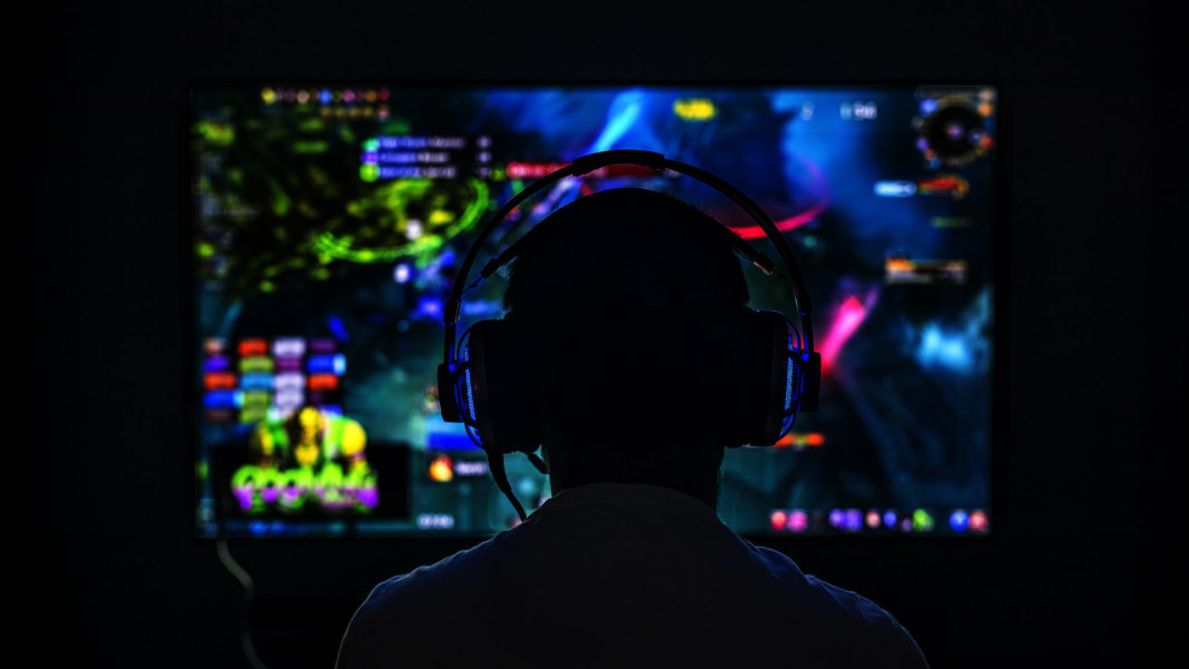 an image of a man with a headset looking at a gaming screen