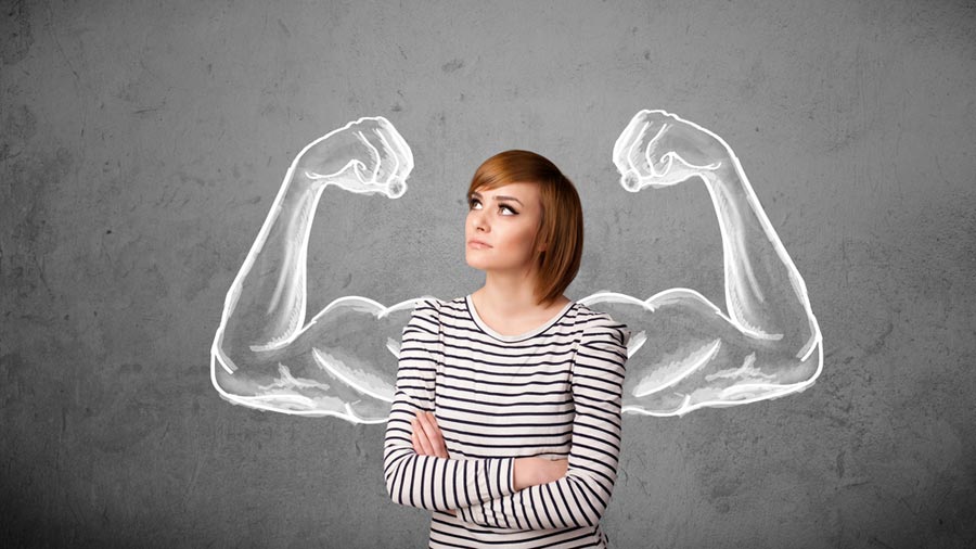 an image of a woman standing with her arms crossed looking upwards with two muscular arms drawn on the wall behind her to signify working on your will power